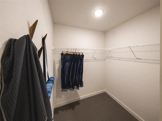 Walk-in closet with a wooden coat rack and a hanging rod with jeans.