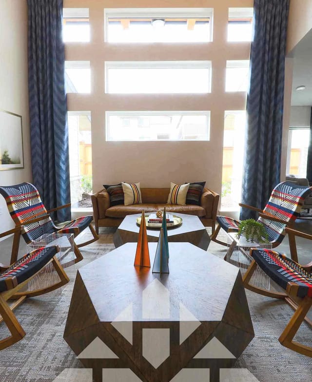 Living room with leather sofa, unique coffee tables, and colorful chairs.