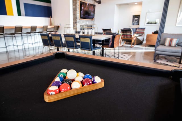 Billiards table with balls racked in a triangle in a community lounge area.