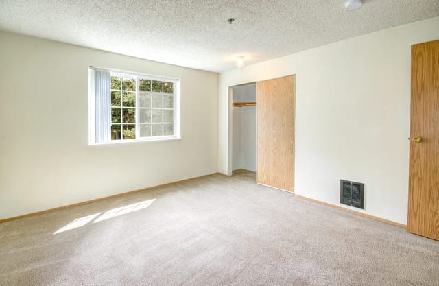 Empty apartment bedroom with a closet and window.