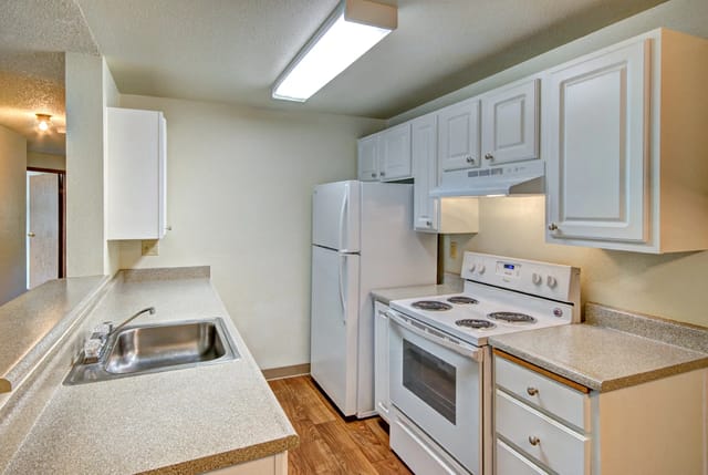 Kitchen with white cabinets, refrigerator, stove, and sink.
