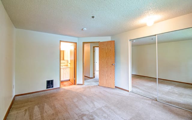 Bedroom with mirrored closet doors and access to bathroom
