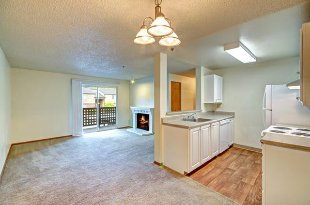 Living room and kitchen area with fireplace and balcony view.
