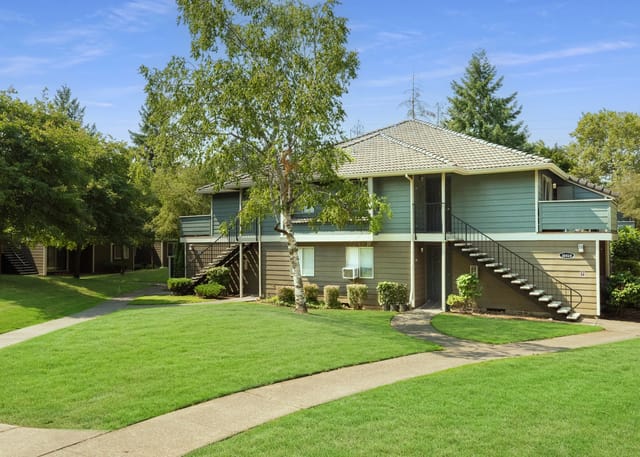 Exterior view of apartment buildings with lush green lawns and mature trees.