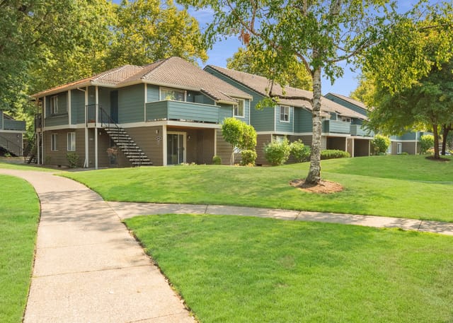 Exterior view of apartment buildings with walkways and green lawns.