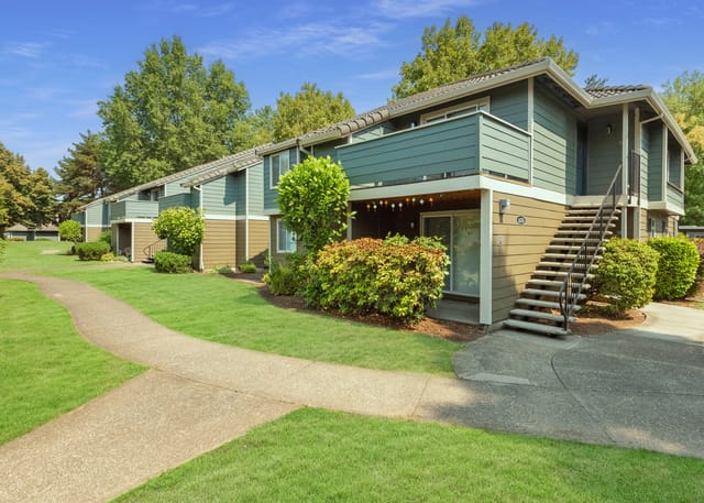Exterior view of apartment buildings with a winding path and lush greenery.