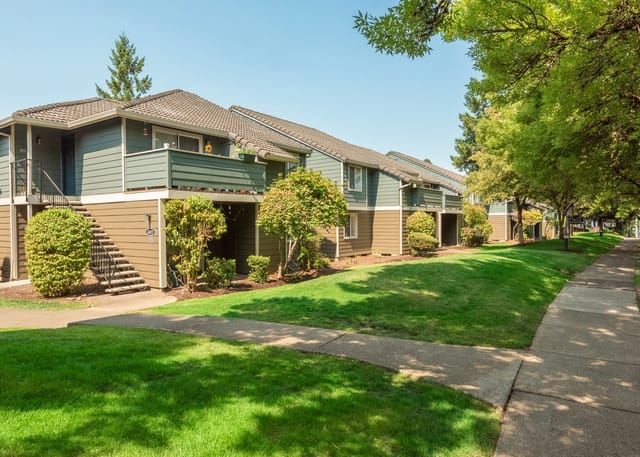 Exterior view of apartment buildings with manicured lawns and sidewalks.
