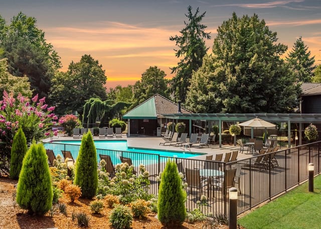 Community swimming pool with lounge chairs and umbrellas at sunset