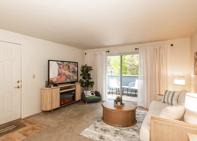 Living room with a couch, coffee table, TV, and balcony access.