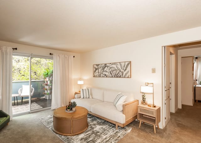 Living room with a sofa, coffee table, and balcony access.