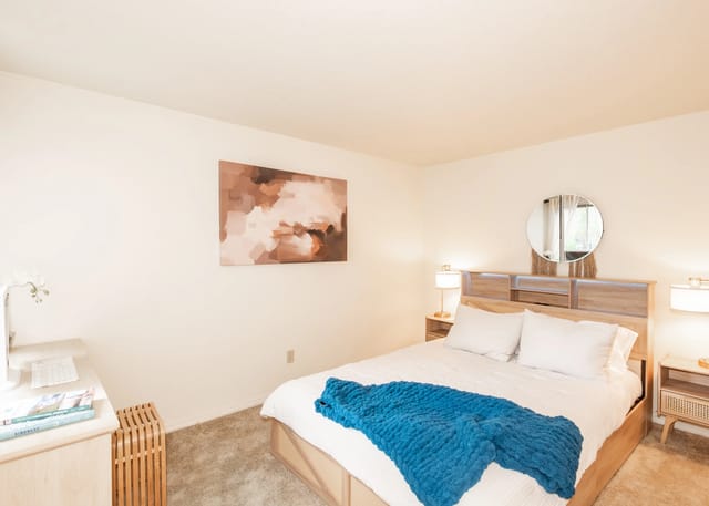 Cozy bedroom with a queen-sized bed, plush blue throw, and a modern desk.