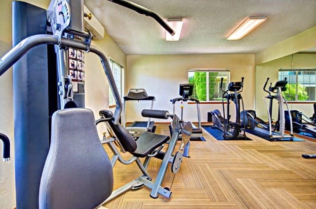 Gym with weight machines, treadmills, and elliptical trainers.