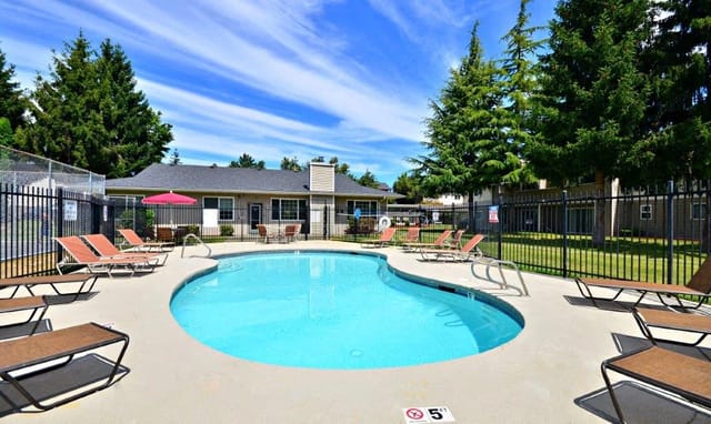 Swimming pool with lounge chairs and umbrellas at an apartment complex.