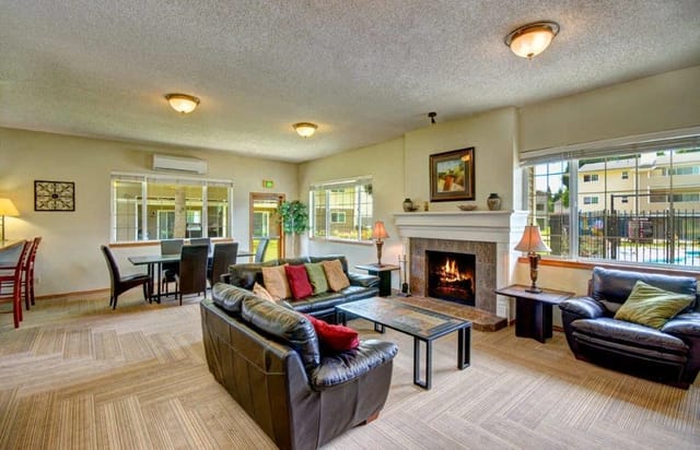 Cozy community lounge with a fireplace, comfortable seating, and a dining area.