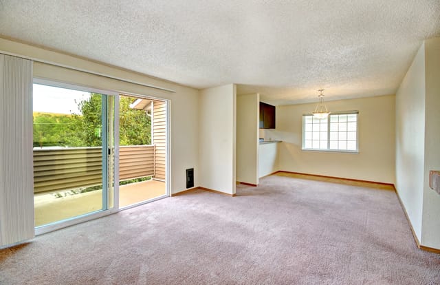 Living room with sliding glass door to balcony and view of trees.