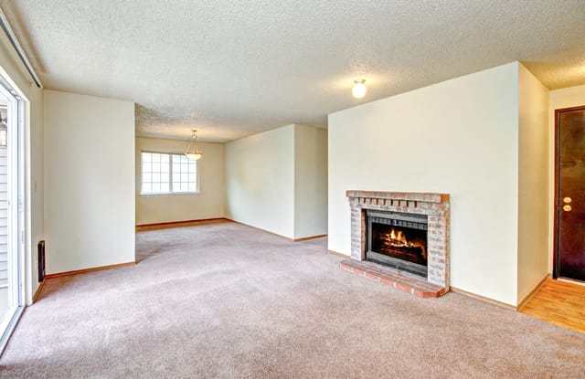 Spacious living room with a brick fireplace and a sliding glass door.