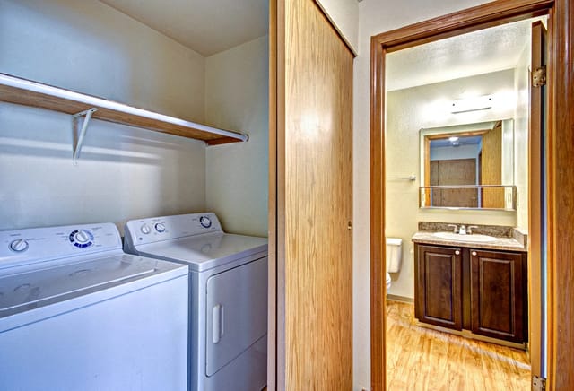 In-unit washer and dryer with overhead shelf and adjoining bathroom.
