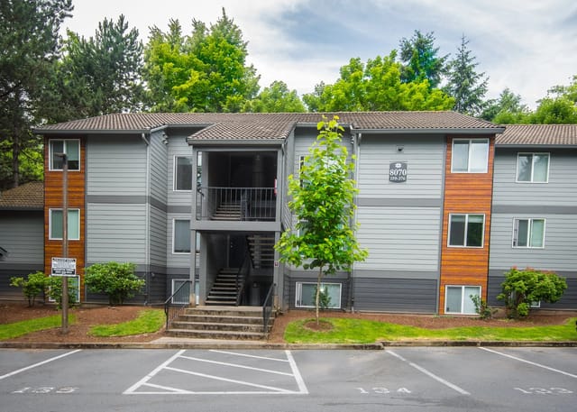 Exterior of a multifamily apartment building with gray siding and wood accents.
