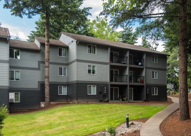 Exterior view of a multi-story apartment building with gray siding and balconies.