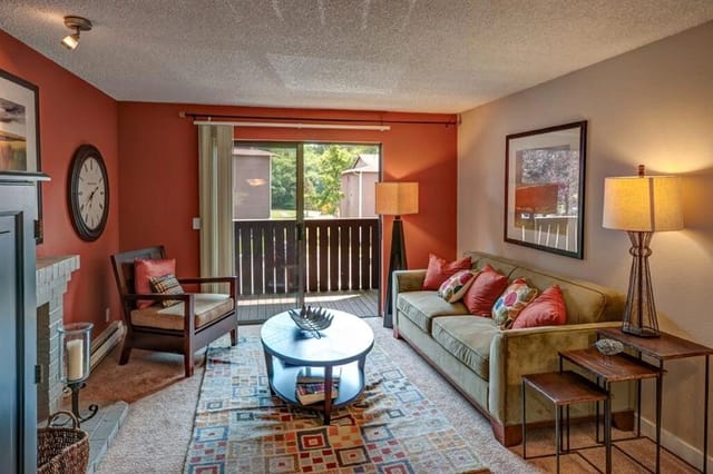 Living room with a sofa, armchair, coffee table, and a balcony view.