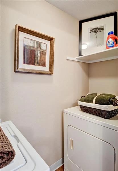 Laundry room with a white washer and dryer, decorated with framed art and a basket of clean towels.