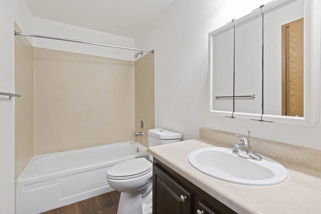 Modern bathroom with a bathtub, toilet, and vanity with a mirror.