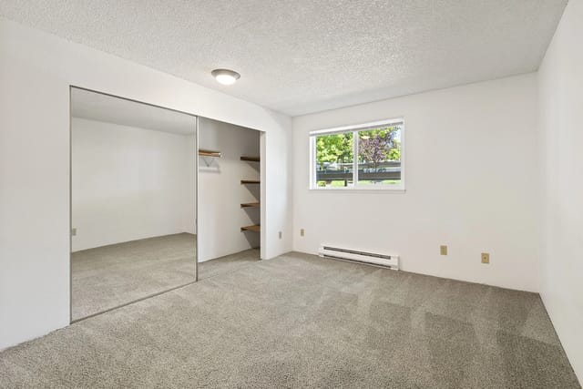 Bedroom with mirrored closet and window.