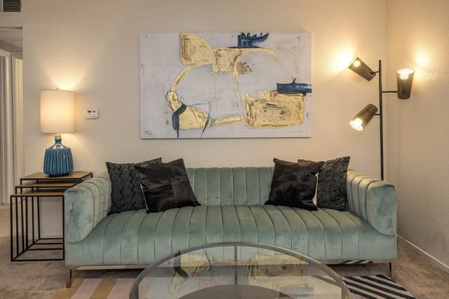 Light blue sofa with black and gold accent pillows in a modern living room.