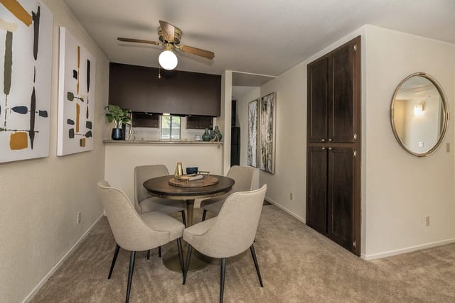 Dining area with a round table and four chairs, next to a kitchen counter.