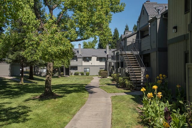 Apartment building exterior with trees and a pathway