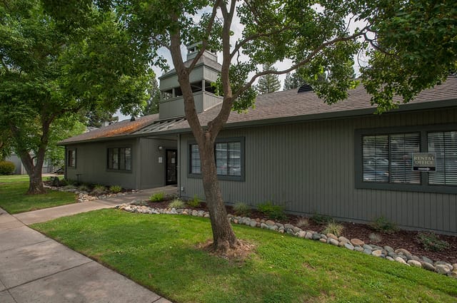 Exterior view of the rental office with a green lawn and trees.
