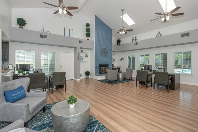 Community lounge area with fireplace, seating, and view of the pool.