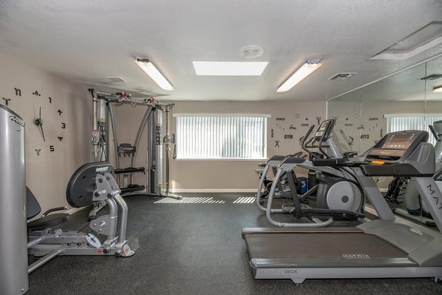 Fitness center with treadmills, elliptical machines, a cable crossover machine, and a leg press.