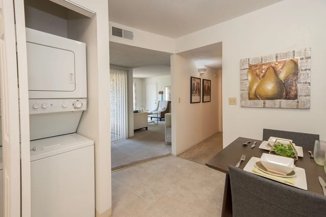 Stackable washer and dryer in a closet, with a view into the dining area and living room.