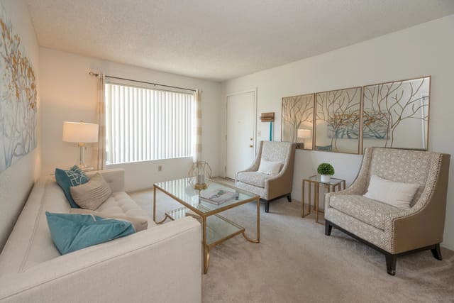 Living room with a couch, two chairs, coffee table, and a large window.