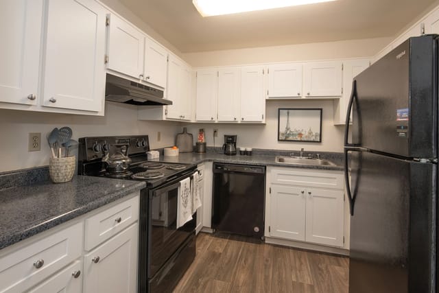 Kitchen with white cabinets, black appliances, and granite countertops.