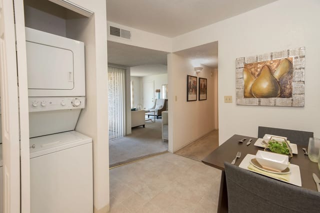 Stacked washer and dryer in a closet beside the dining area; living room visible in the background.