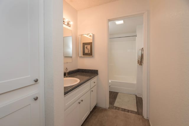 Bathroom vanity with granite countertop, sink, and mirrors.