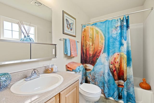 Modern bathroom with a sink, toilet, and shower with a hot air balloon shower curtain.