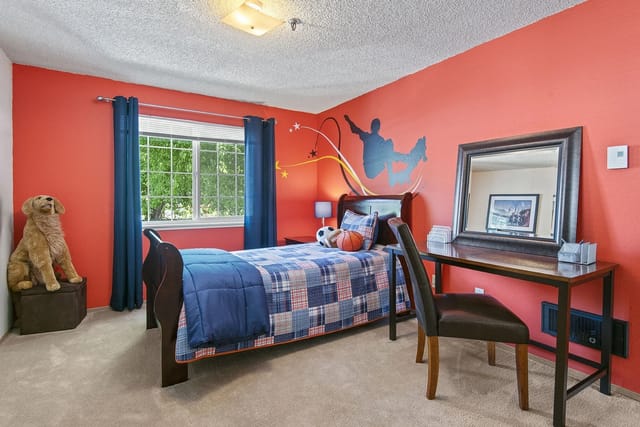 Bedroom with a skateboarder mural, bed, desk, and stuffed dog.