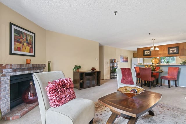 Living room with fireplace, dining area, and kitchen view.