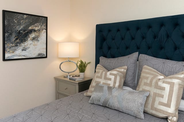Modern bedroom with a plush tufted headboard, decorative pillows, and abstract wall art.