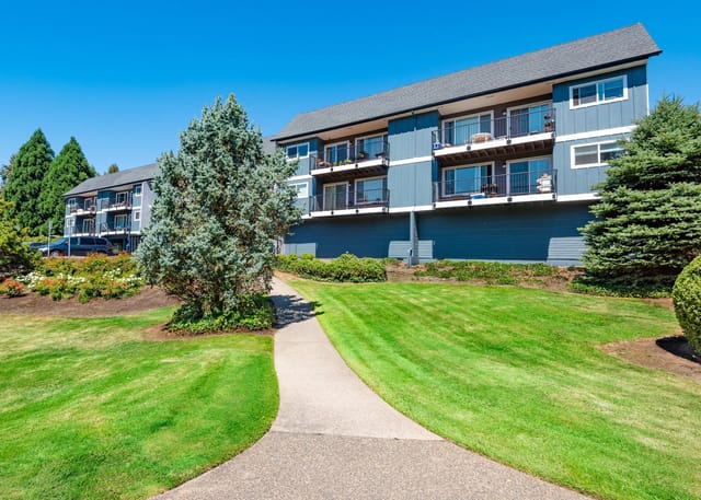 Exterior of apartment buildings with balconies and lush green lawns and a walking path.