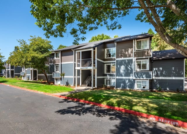 Exterior view of apartment buildings with lush green lawns and trees.