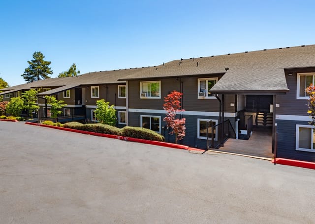 Exterior view of a multifamily apartment building with dark gray siding and white trim.