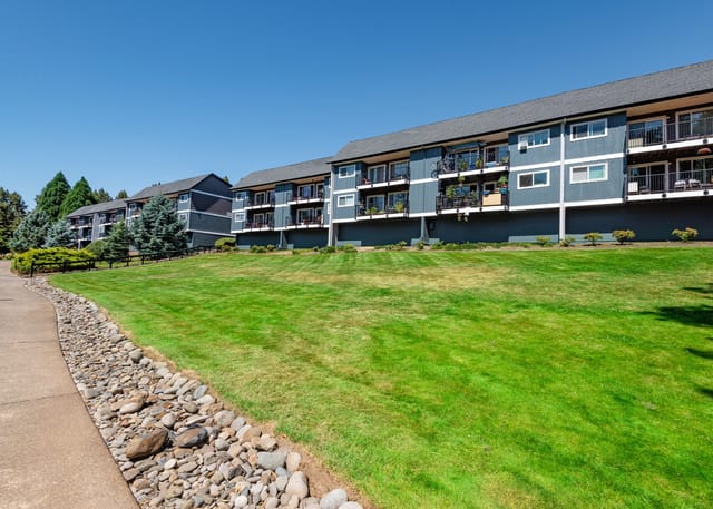 Exterior view of apartment buildings with balconies and manicured lawns.