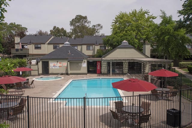 Outdoor swimming pool and hot tub with lounge chairs and umbrellas.