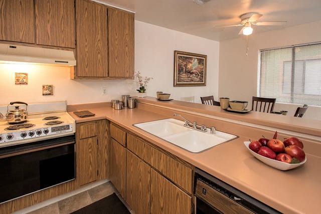 Kitchen with wooden cabinets, white countertops, and a double sink.