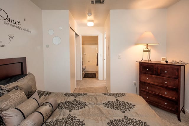 Bedroom with a dresser and a doorway to the bathroom.