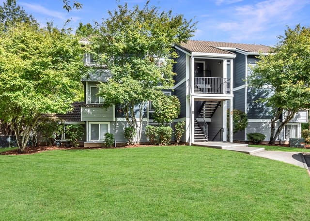 Exterior view of apartment buildings with lush green lawns and trees.